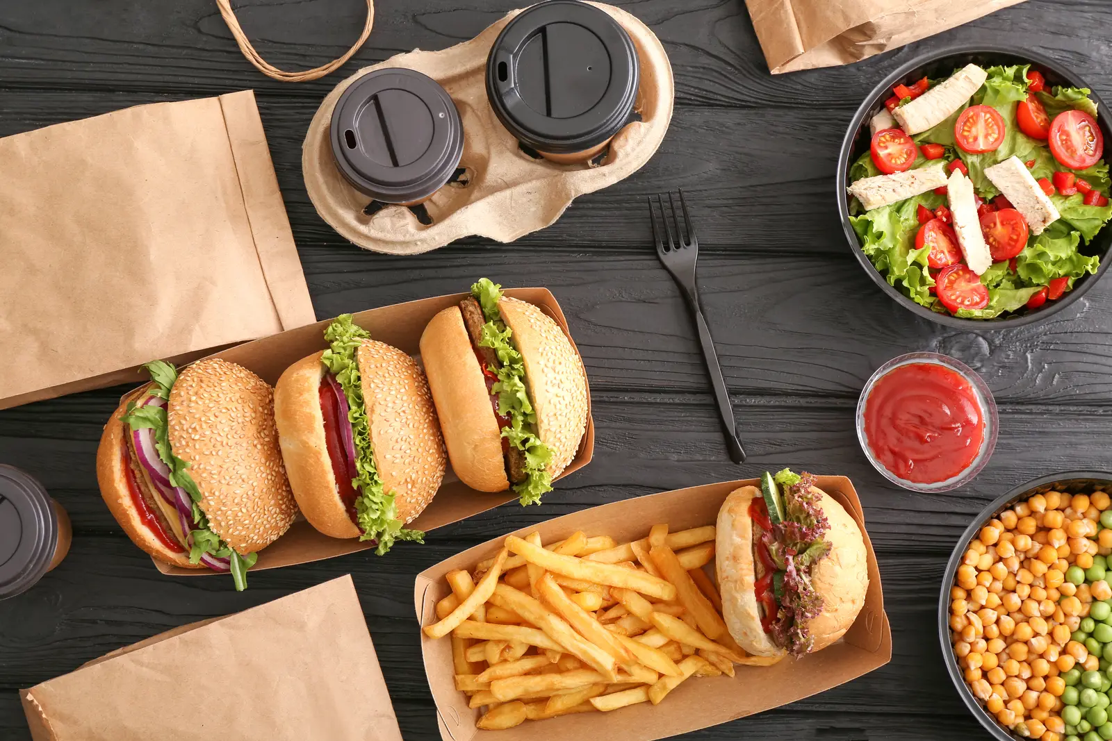 Gros plan sur un assortiment d'emballages alimentaires professionnels variés posés sur un plan de travail en inox